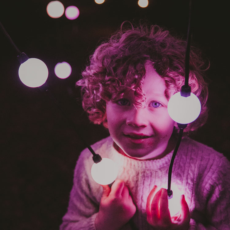 A child smiling among glowing pink orbs of light