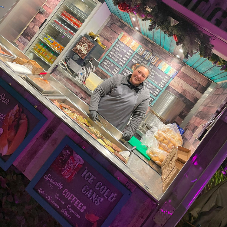 A trader smiling from the counter of his festive food stall