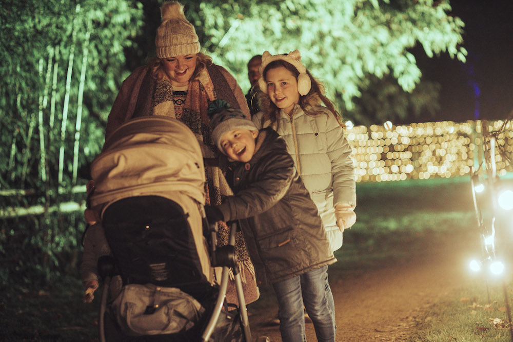 A family with a pushchair on a lit woodland path